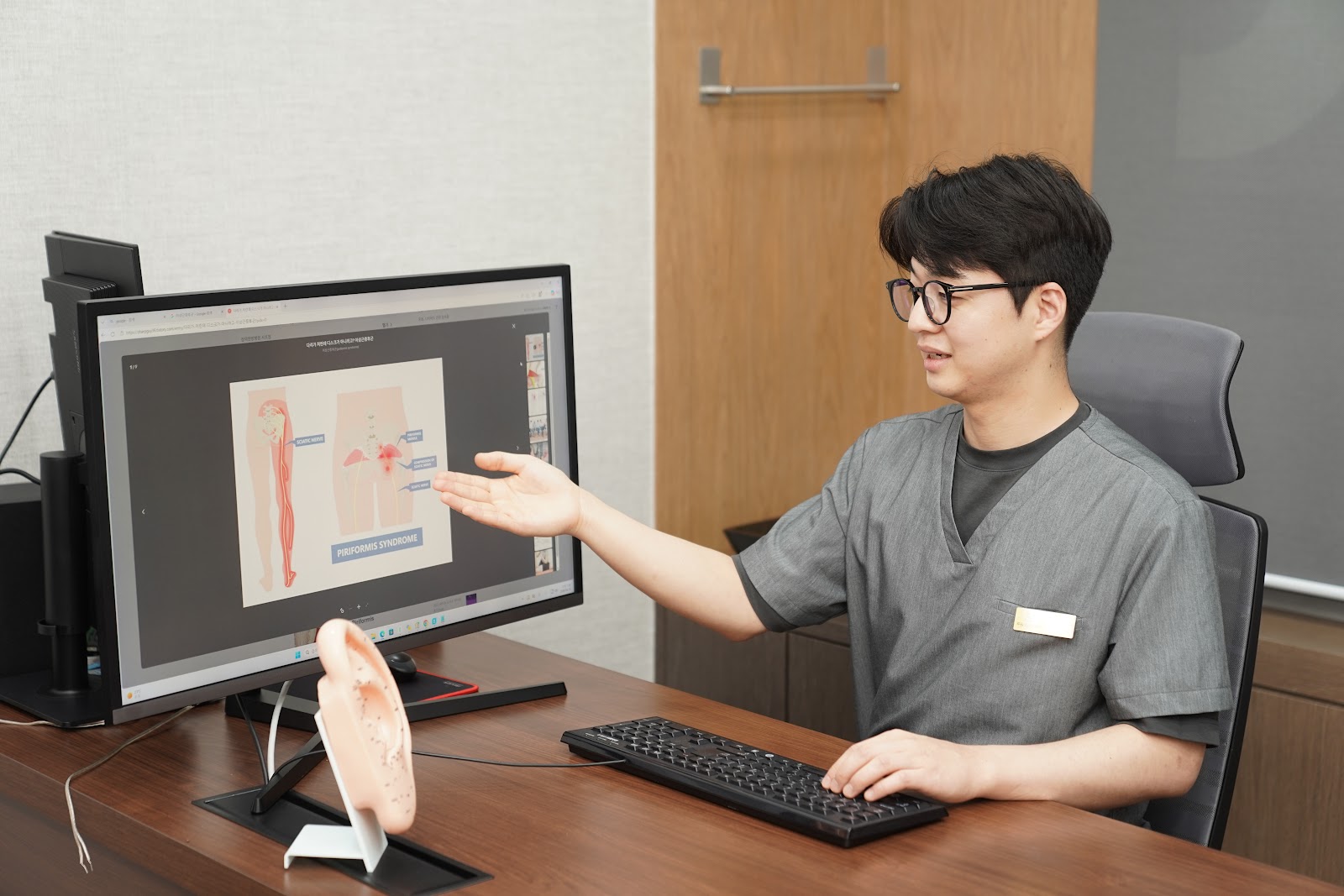 한의사가 척추 모형과 화면을 함께 보며 상태를 설명하는 모습